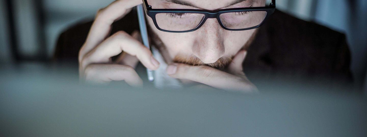 Mann mit Brille vorm PC telefoniert im Recruitingprozess 